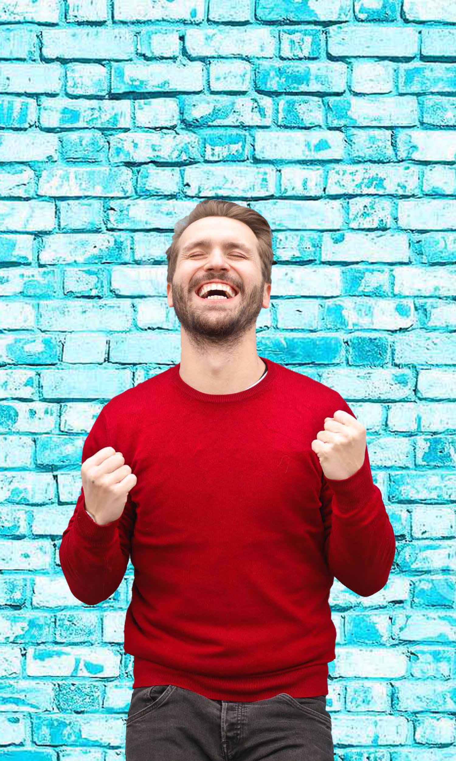 excited man in front of a blue brick wall